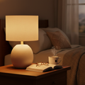 Ceramic Glow Table Lamp with warm amber light on wooden nightstand