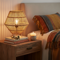 Rattan weave bedside lamp glowing warmly on a wooden nightstand
